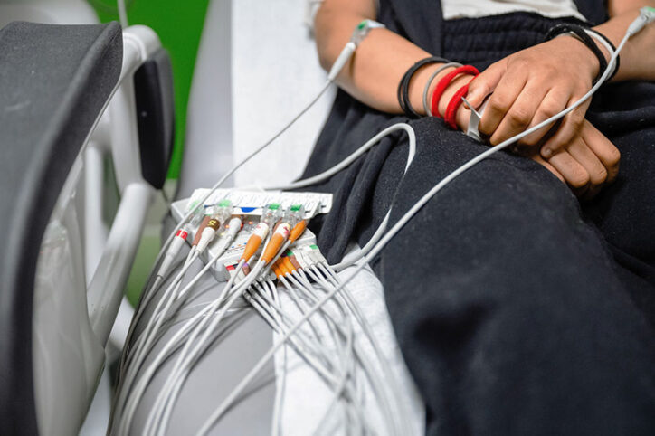 Sensors from an ECG machine are placed on the arms of a patient who is seated.