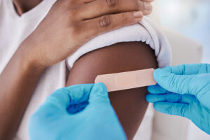 two gloved hands applying a bandaid to a child's upper arm