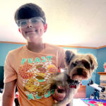 A preteen boy holding a small dog.