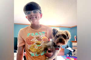 A preteen boy holding a small dog.