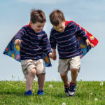 Two young boys wearing superhero capes