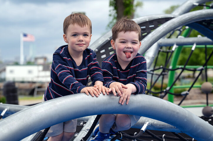 Two young boys playing on a jungle gym at a park