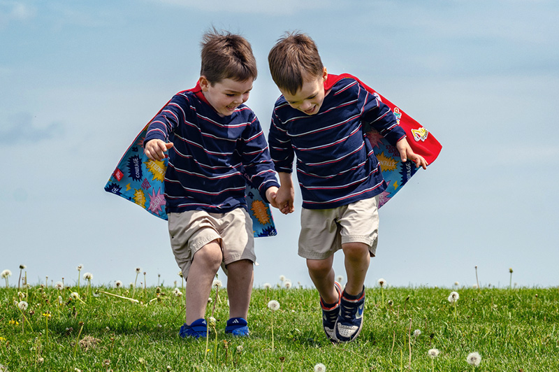 Two young boys wearing superhero capes