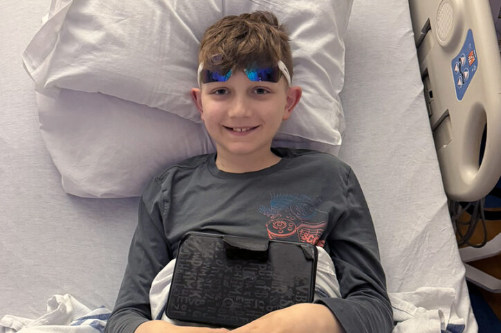 A smiling preteen boy in a hospital bed