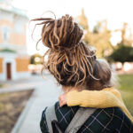 woman holding young girl while walking outside