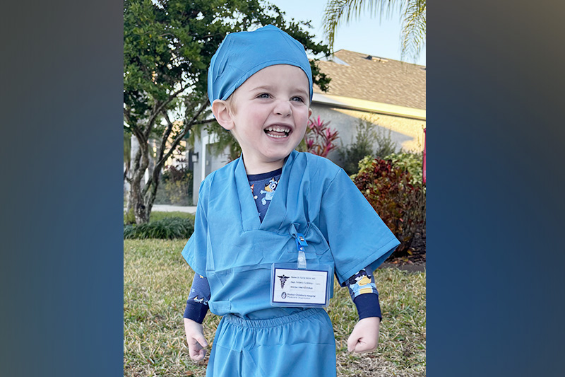 A young boy is dressed in blue surgical scrubs.