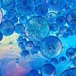 Clusters of overlapping bubble-like droplets in different sizes on a liquid surface.