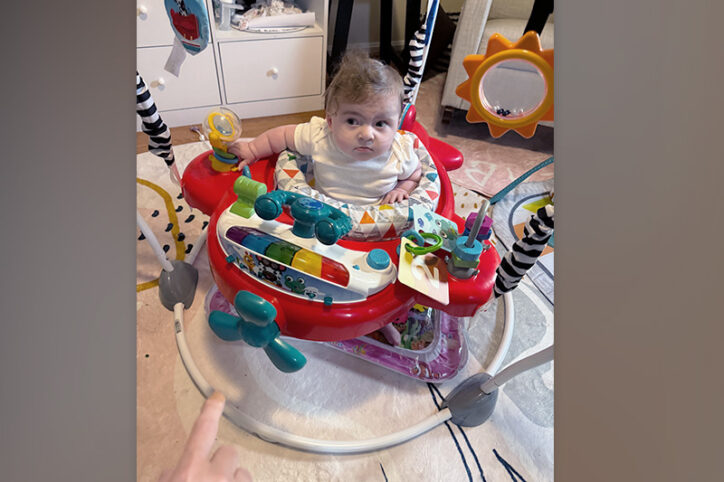 An infant girl sits in an activity jumper.