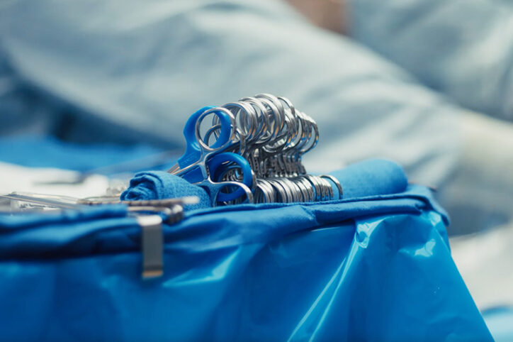 Several pairs of surgical scissors sit on top of an operating room tray.