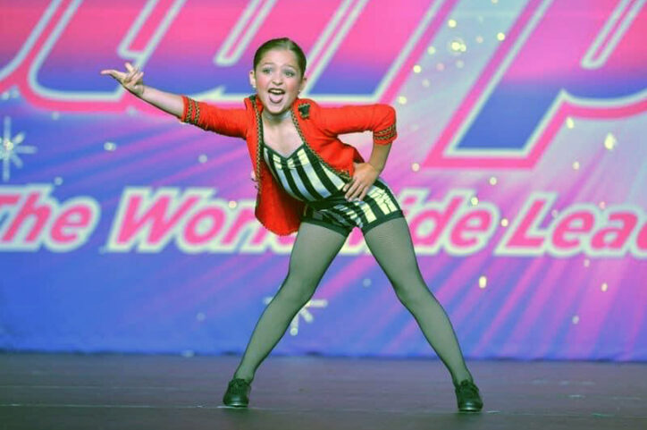 A preteen girl posing on stage during a dance routine