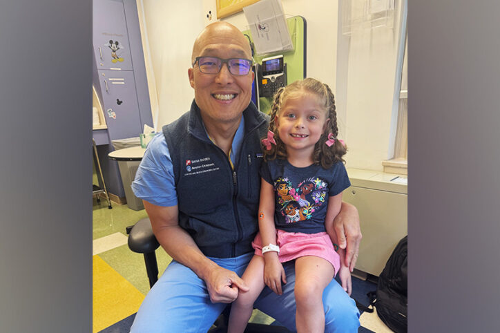 A young girl and a physician sit smiling together.
