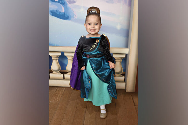 A young girl dressed up like a princess with a castle-like setting in the background. 