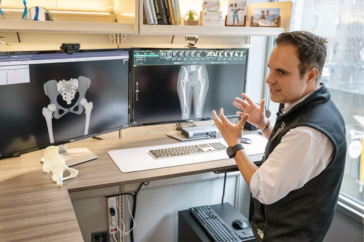 An engineer in front of two computer screens showing an MRI image and a 3D image.