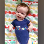 a baby in a onesie that reads, 