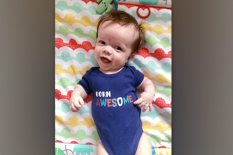 a baby in a onesie that reads, "Born Awesome"