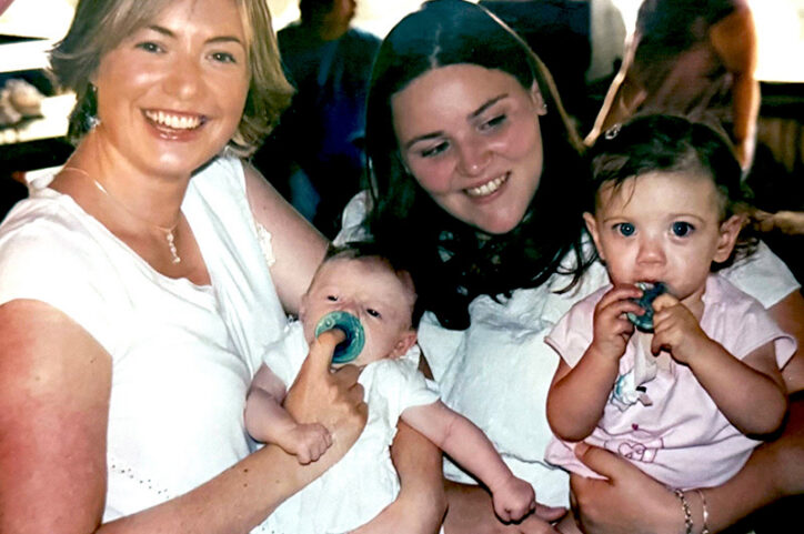A woman cradling a baby next to a woman holding a toddler girl.