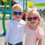 two young children smiling and wearing sunglasses