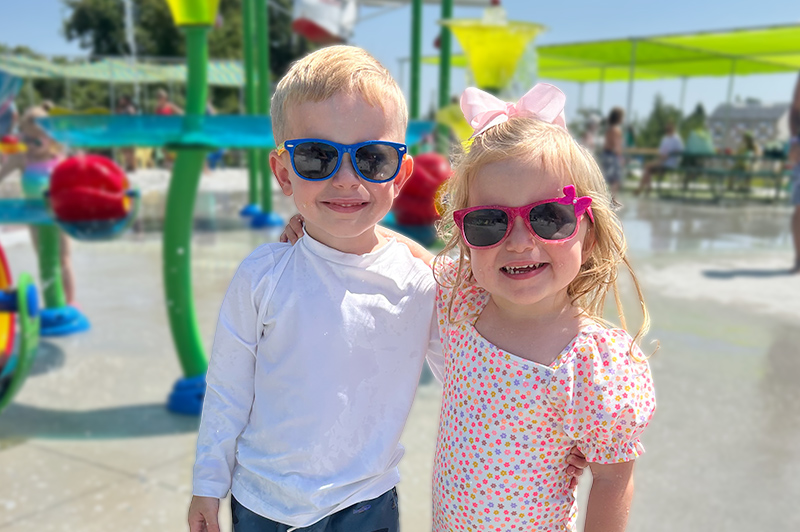 two young children smiling and wearing sunglasses