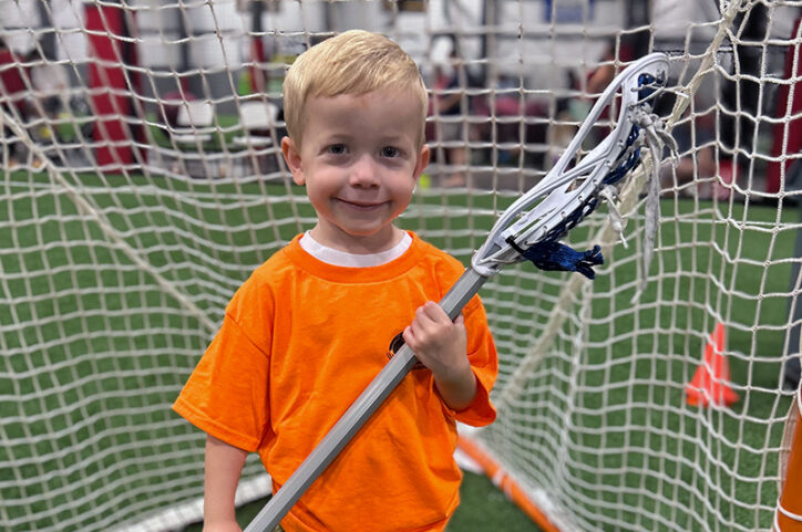 a young boy holding a lacrosse stick