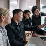 Four clinicians reviewing neonatal brain imaging on a computer in an office.