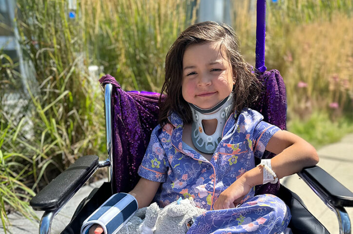 a 6-year-old girl sits in a wheelchair and wears a neck brace
