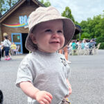A young boy wearing a bucket hat smiles.