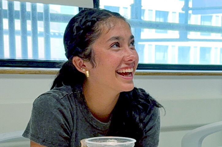 A young woman grins while speaking with someone.