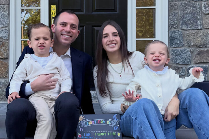 A father, mother, young boy, and toddler girl smile at the camera