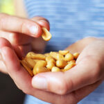 A person holds a handful of peanuts while picking one up with the other hand.