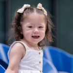 a young girl with ponytails smiling at the camera