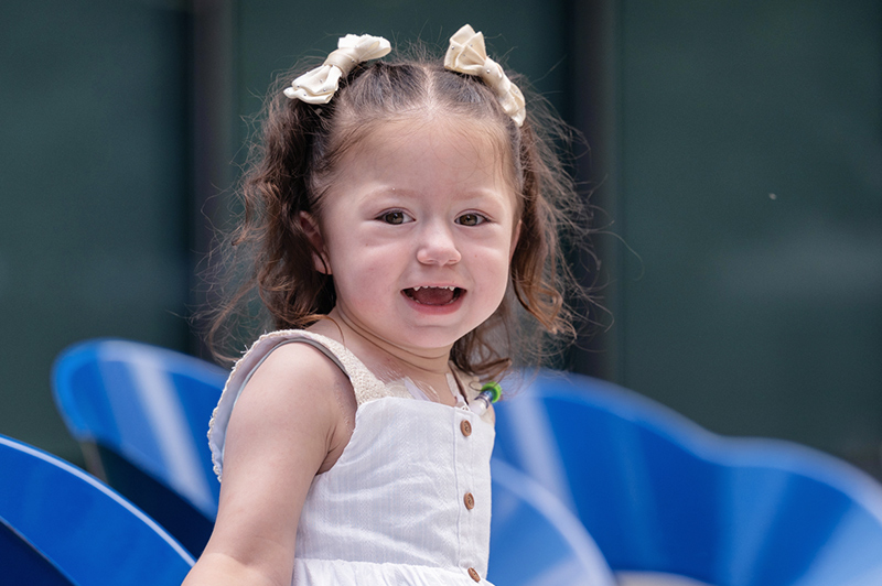 a young girl with ponytails smiling at the camera