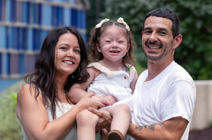 A smiling young girl with her mother and father