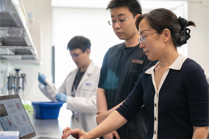 Three members of a lab team work together.